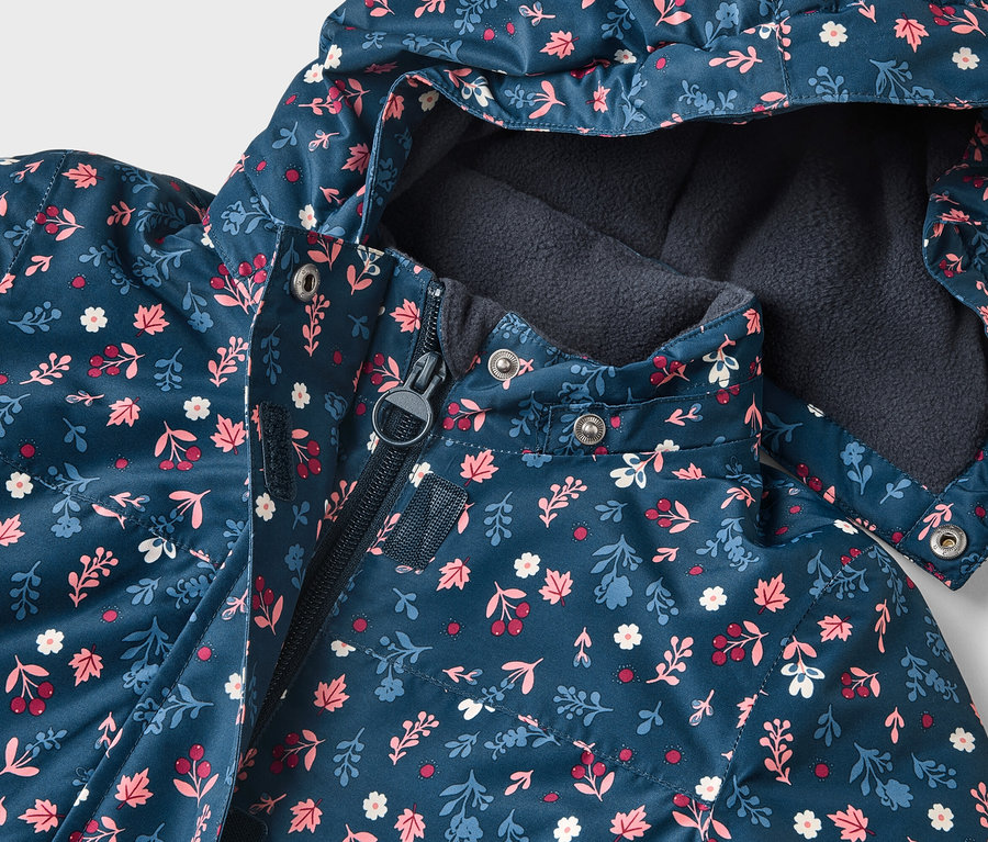 Nahaufnahme einer marineblauen, blumengemusterten Jacke mit Kapuze, die teilweise mit einem Reißverschluss geschlossen ist.