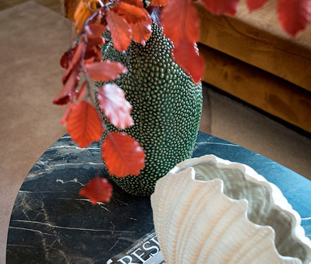 Nahaufnahme einer Vase mit Ästen und einer dekorativen Schale in Muschelform auf einem Marmortisch. Die Vase ist eine Vase »Shell«.