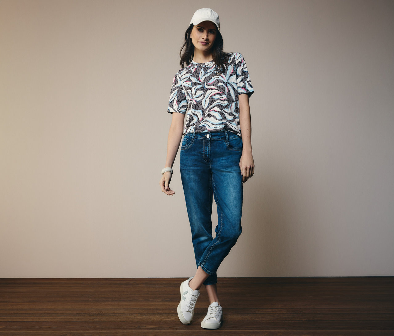 Frau in blauem CECIL Kurzarmshirt und CECIL Jeans »Scarlett«, dazu weiße Schuhe und Kappe.