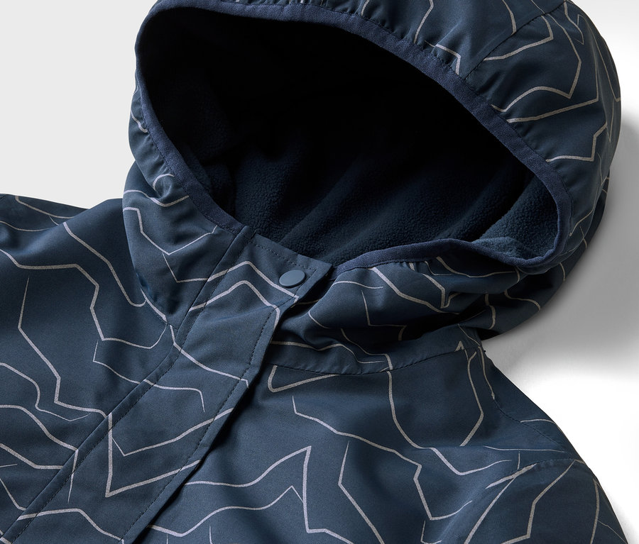 Nahaufnahme einer marineblauen Jacke mit Kapuze und weißem geometrischen Muster. Die Kapuze ist mit marineblauem Fleece gefüttert.