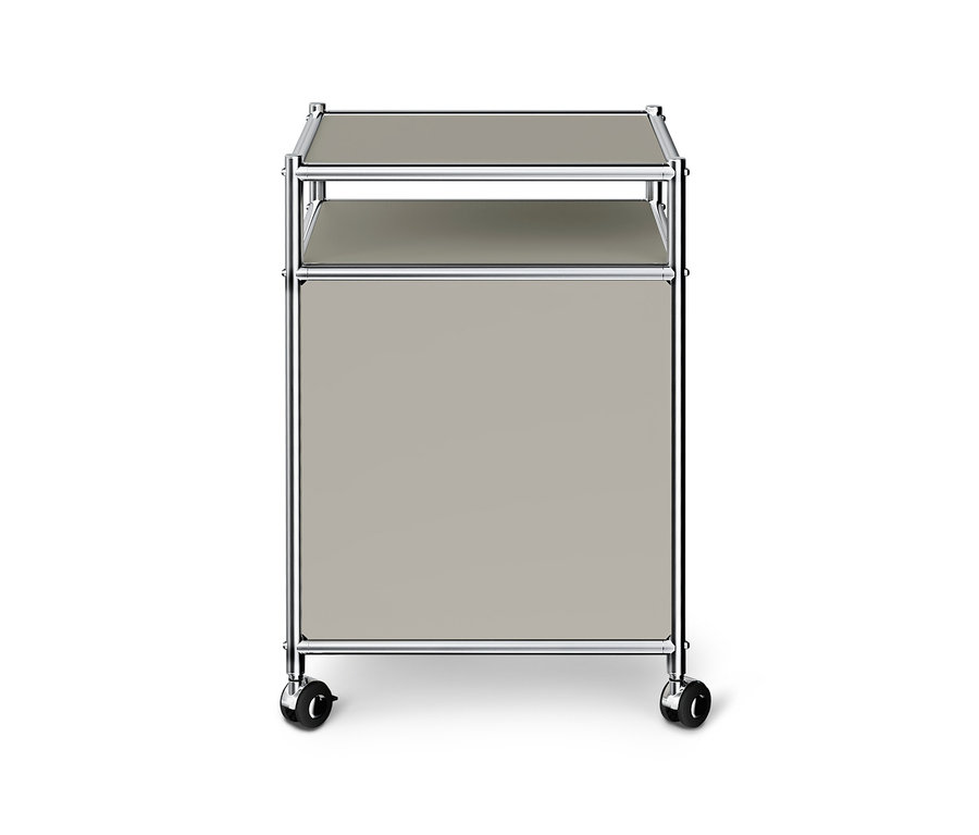 Hellgrauer Rollcontainer mit Chromgestell, zwei Ablagen und einem geschlossenen Fach auf Rollen.
