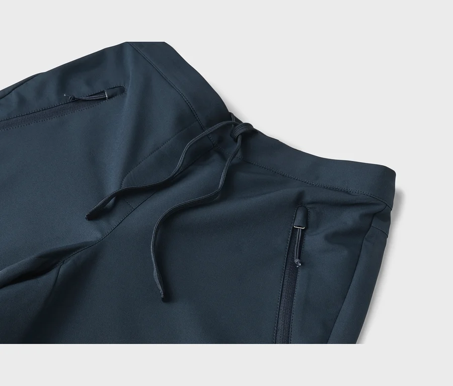 Nahaufnahme einer dunkelblauen Hose mit Kordelzugbund und Reißverschlusstaschen.