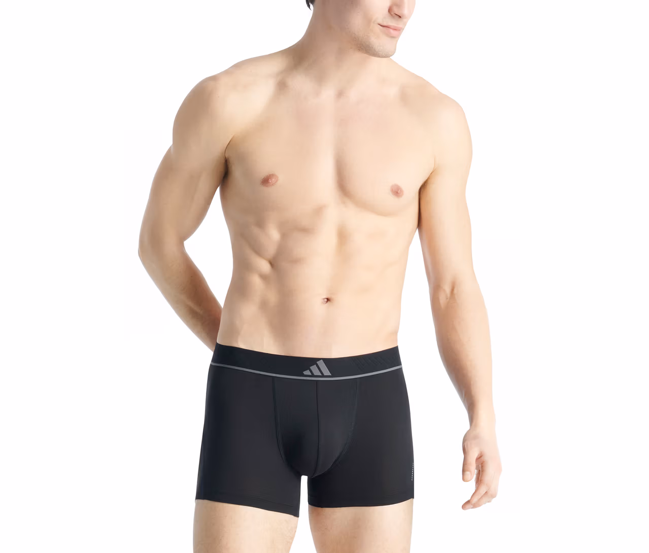 Oberkörperfreier Mann mit muskulösem Oberkörper trägt schwarze Boxershorts mit grauem Adidas-Logo am Bund.