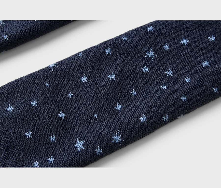 Nahaufnahme eines dunkelblauen Stoffes mit kleinen, hellblauen Schneeflockenmustern.