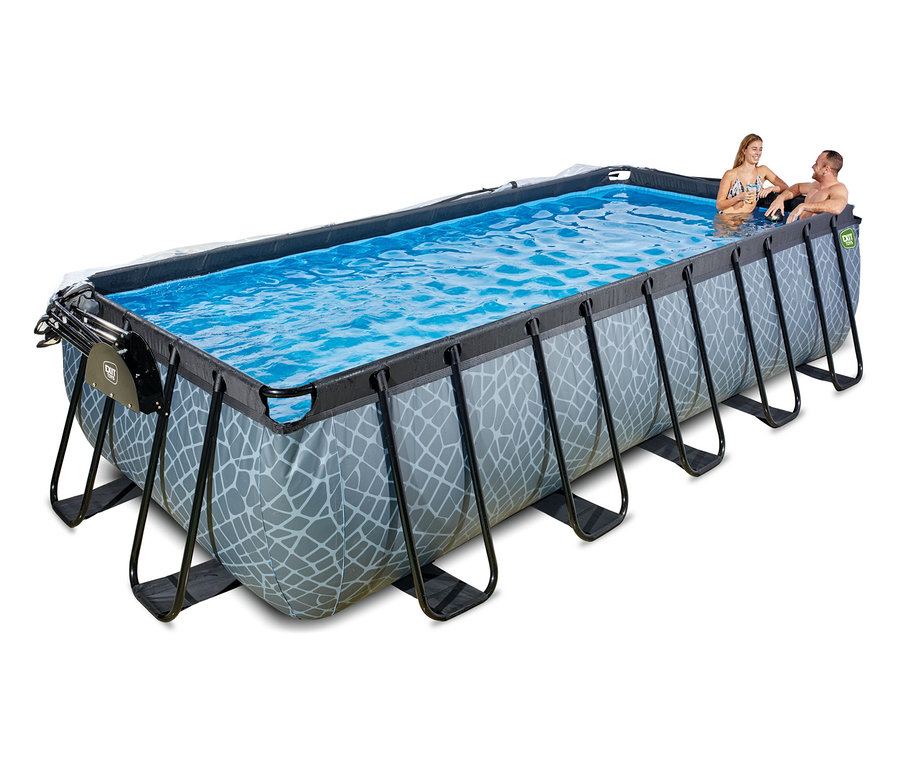 Ein Mann und eine Frau sitzen im blauen Wasser eines rechteckigen EXIT Pool-Sets in Steinoptik (540 x 250 cm). Der Pool hat eine graue Außenseite mit weißem geometrischem Muster und schwarzen Stützrahmen.