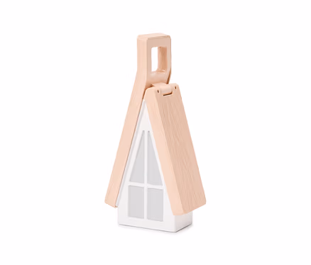 Eine weiße Lampe in Hausform mit einem hellen Holzgiebeldach, das sich oben zu einem Griff zusammenfügt. Die Vorderseite hat ein Fenstergitterdesign.