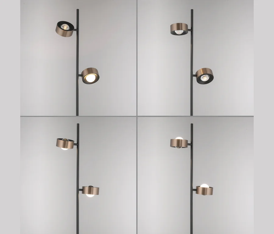 Eine schwarze Stehlampe mit zwei verstellbaren, bronzefarbenen zylindrischen Leuchtenköpfen, in vier verschiedenen Positionen mit eingeschaltetem Licht.