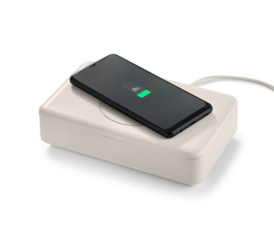 Ein Handy liegt auf der UV-Desinfektionsbox mit kabellosem Ladegerät.