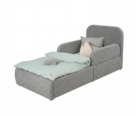 Ein graues Kinderschlafsofa mit strukturiertem Stoff, ausgezogen als Bett. Es hat eine hellgrüne Bettdecke mit weißen Punkten, ein graues sternförmiges Kissen und zwei Rückenkissen, eines hellgrau und eines cremefarben.
