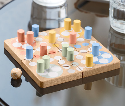 Auf einem Tisch steht ein Ludo-Puzzle mit bunten Spielfiguren und einem Würfel.