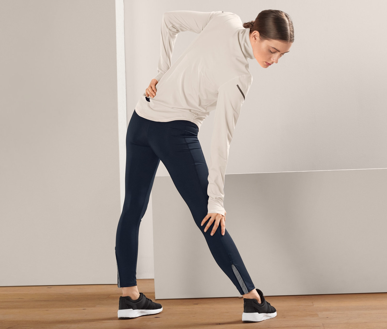 Frau dehnt sich in dunkelblauen Thermo-Lauftights.