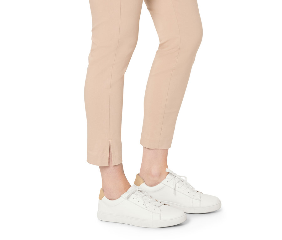 Beine in beigen Hosen und Ledersneaker.