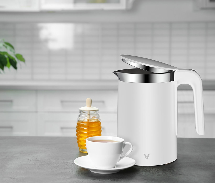 Auf einem Tisch stehen ein weißer Viomi Smart Kettle, ein Glas Honig und eine Tasse Tee.