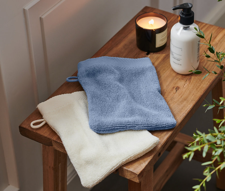 Auf einem Holzhocker liegen zwei blaue und weiße hochwertige Waschlappen.