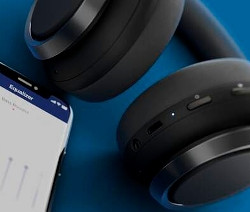 Schwarze Philips Bügelkopfhörer »TAH9505BK/00« liegen neben einem Handy mit geöffneter Equalizer-App auf blauem Hintergrund.