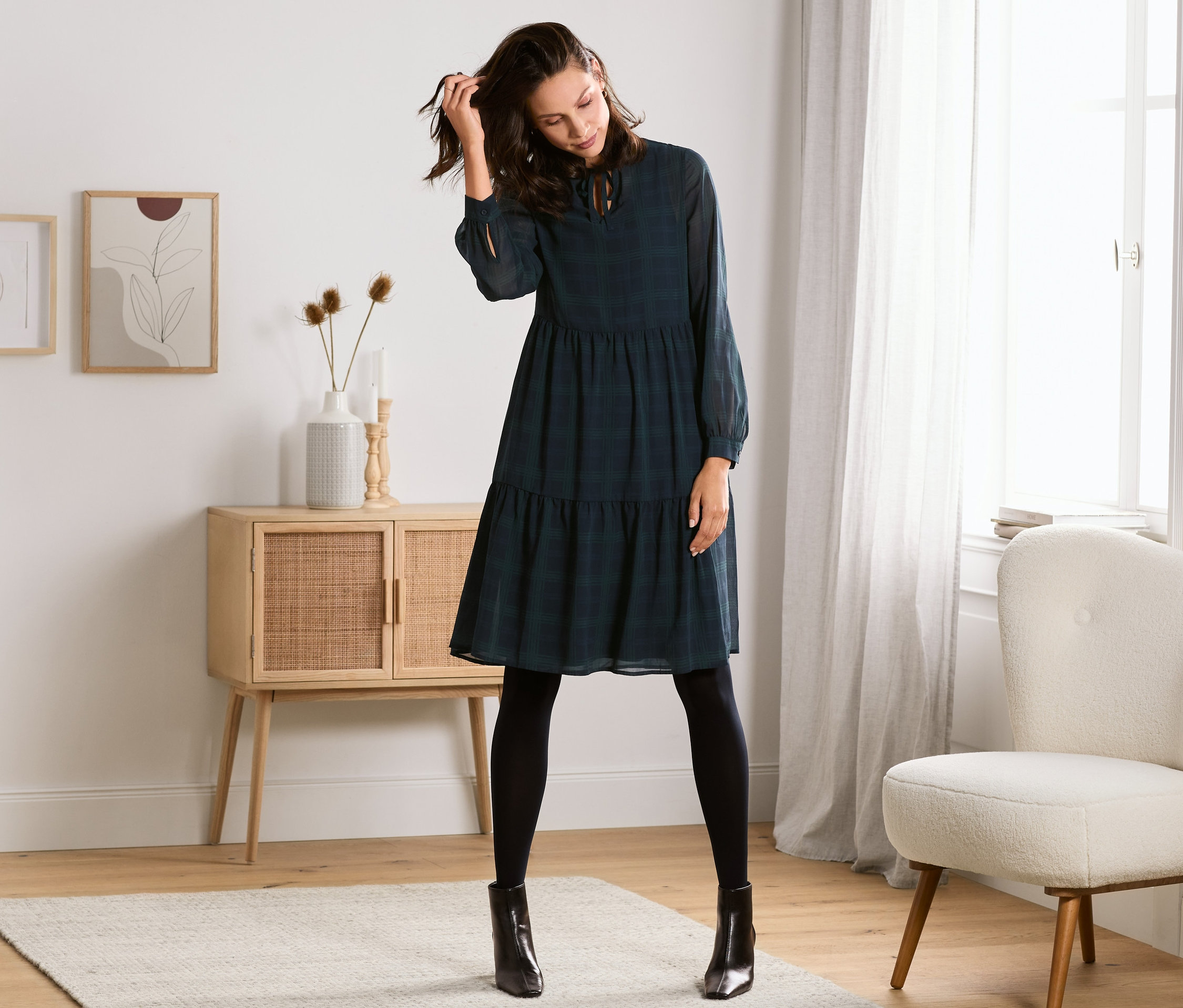 Frau posiert in kariertem Kleid.