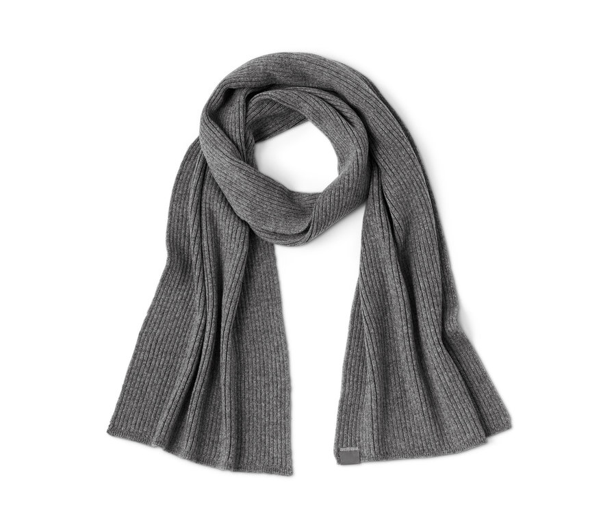 Ein grauer Strickschal liegt auf einem weißen Hintergrund.