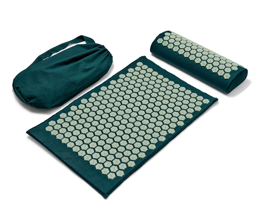 Eine grüne Akupressurmatte, eine Rolle und eine Tasche mit weißen Spitzen.