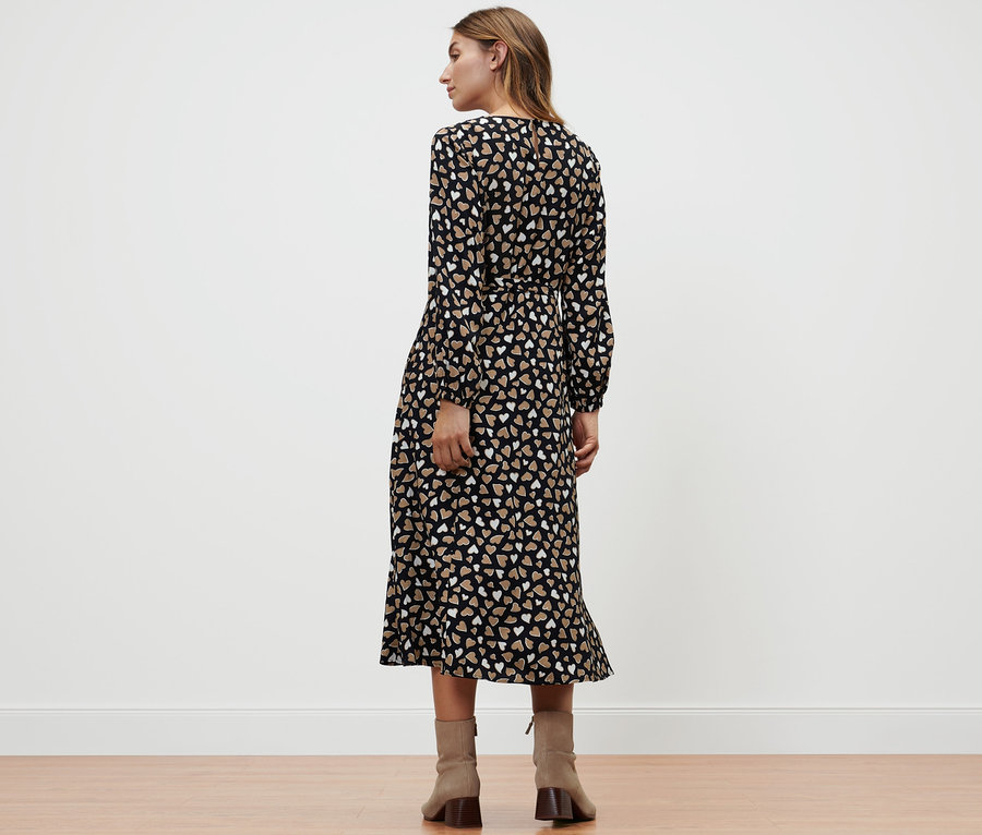 Eine Frau steht mit dem Rücken zur Kamera und trägt ein Webkleid mit Alloverprint.