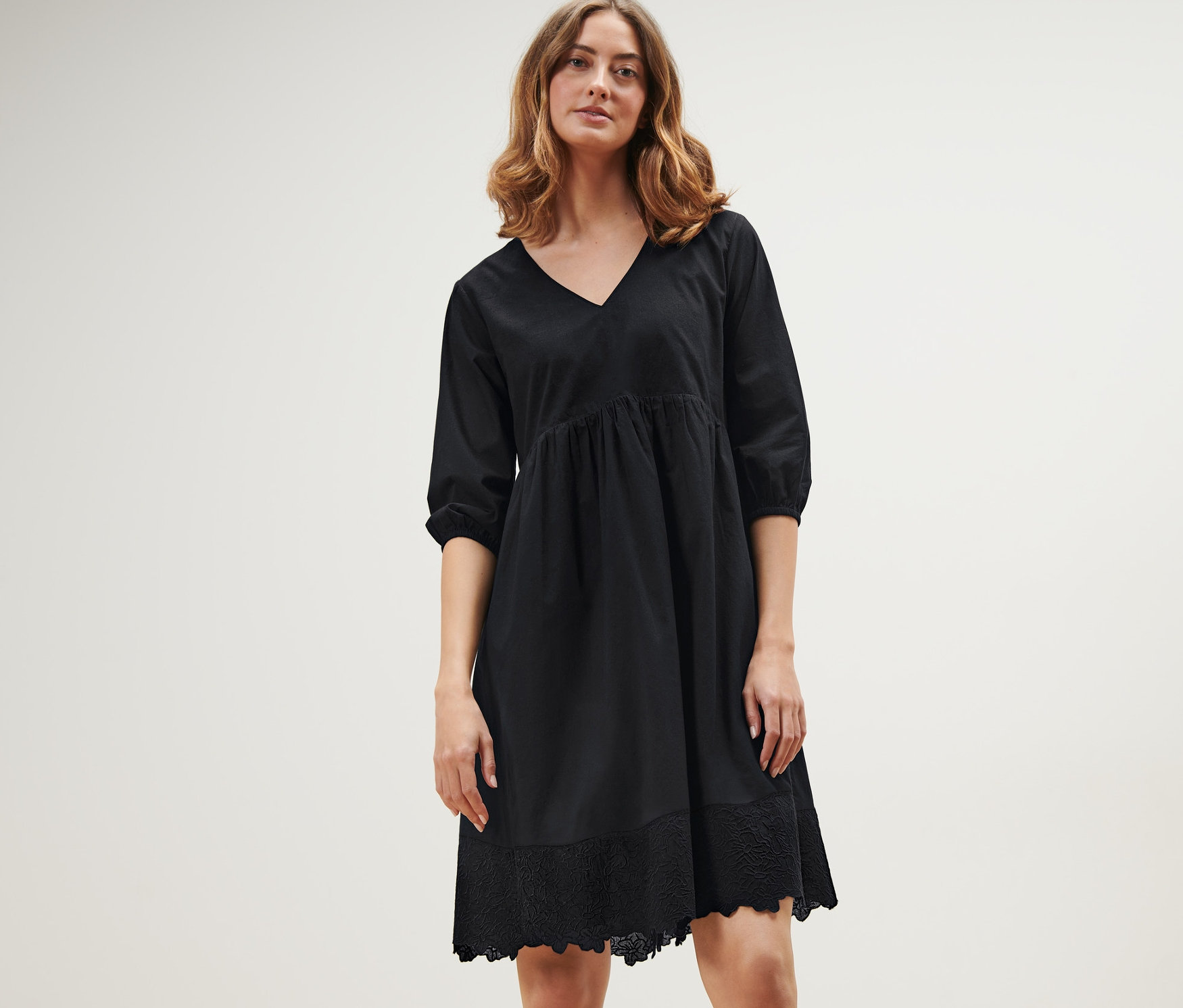 Frau posiert in einem schwarzen Webkleid mit Stickerei.