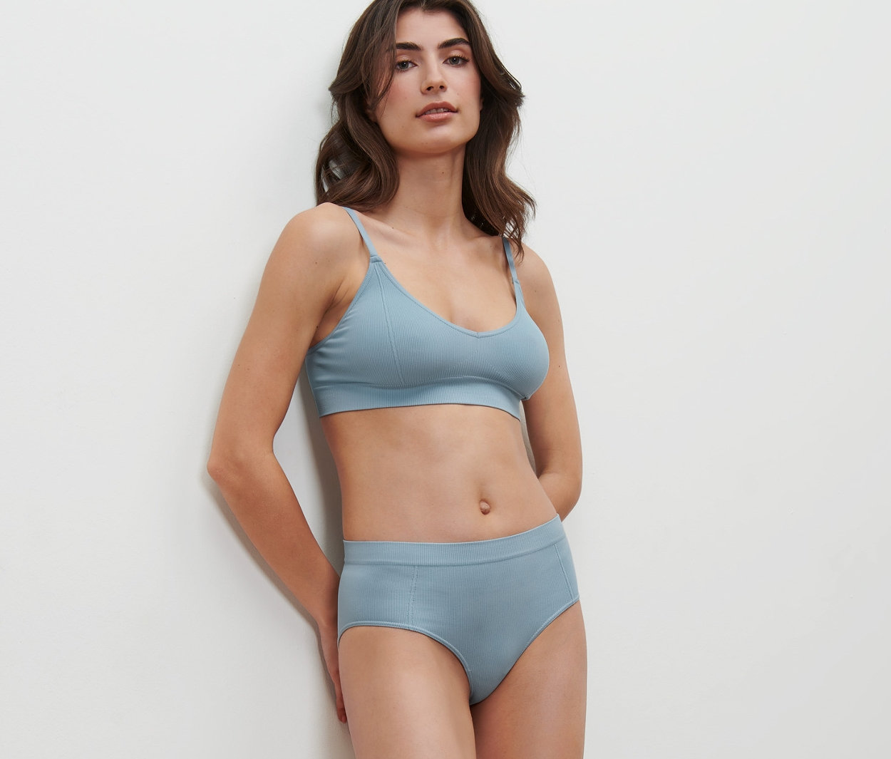 Frau posiert in blauem Seamless-Set mit 2 Seamless-Pantys.