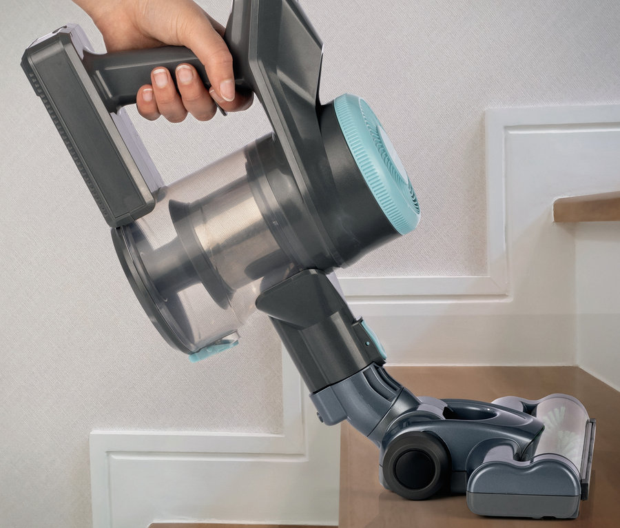 Eine Hand hält einen Akku-Hand- und Bodenstaubsauger auf einer Treppenstufe.