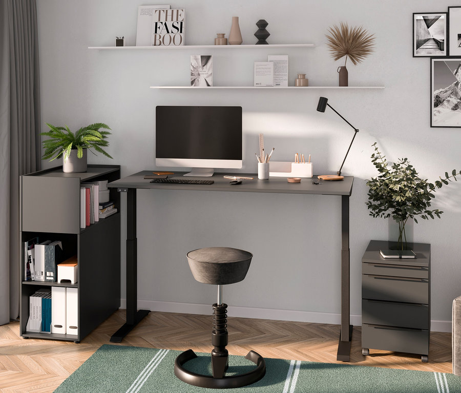 Ein Zimmer mit einem elektrisch höhenverstellbaren Schreibtisch »Kopenhagen«, graphit, einem Rollcontainer »Kopenhagen«, graphit, einem Stuhl und Dekorationen.