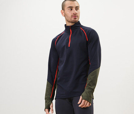 Mann trägt ein Thermo-Funktionsshirt, dunkelblaue Leggings und posiert.