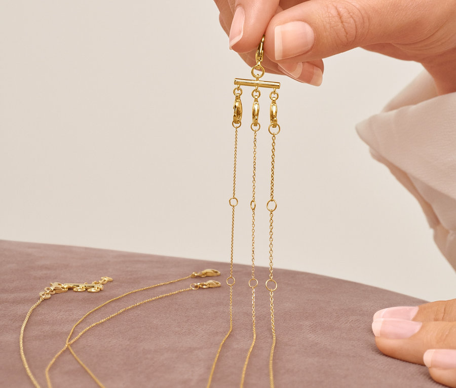 Eine Frau hält zwei Kettenverschlüsse für Layering in der Hand.
