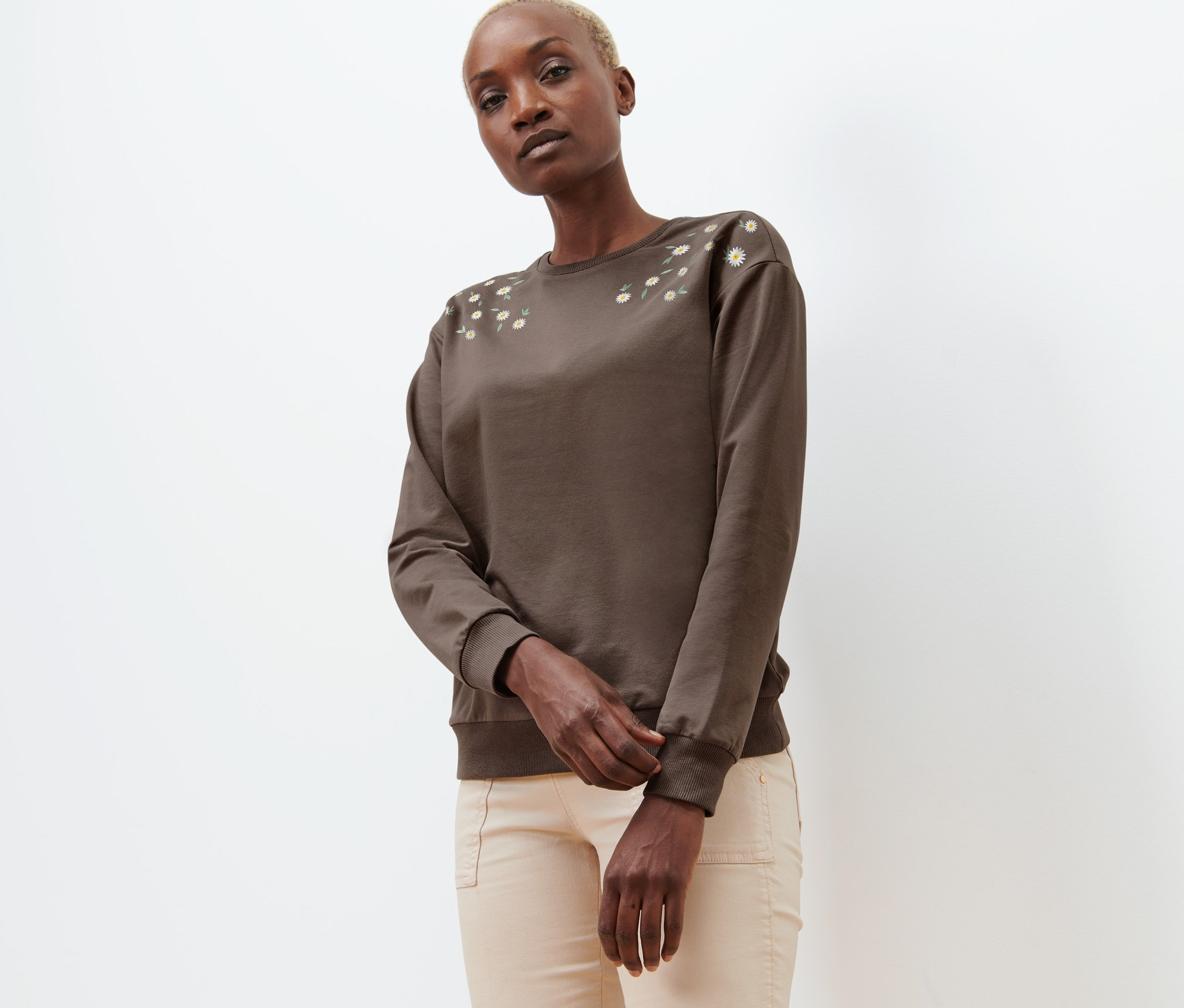 Frau trägt ein braunes Sweatshirt mit Stickerei.