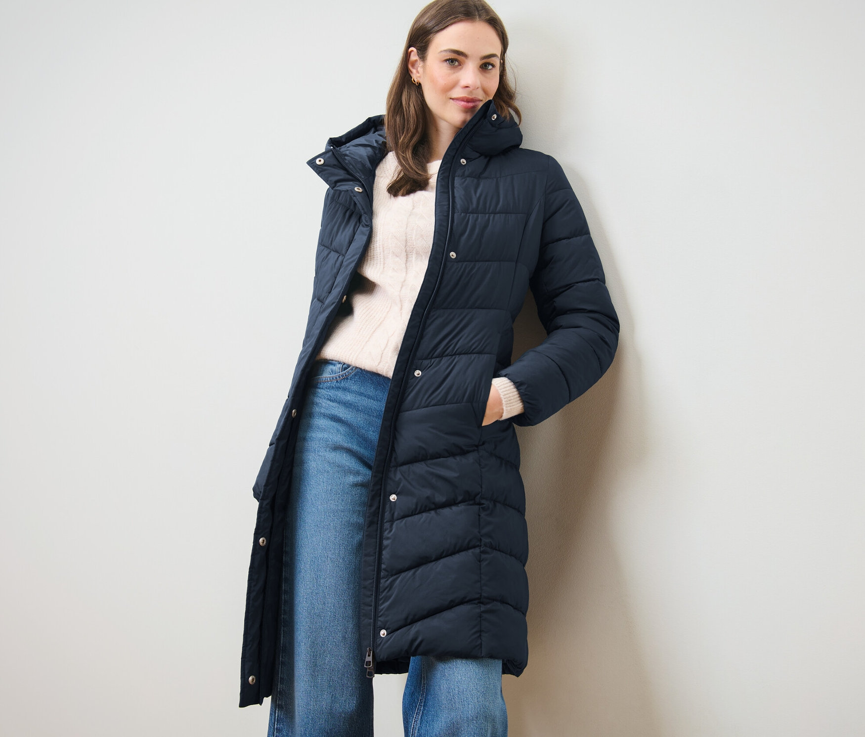 Frau posiert in dunkelblauem Steppmantel mit Kapuze.