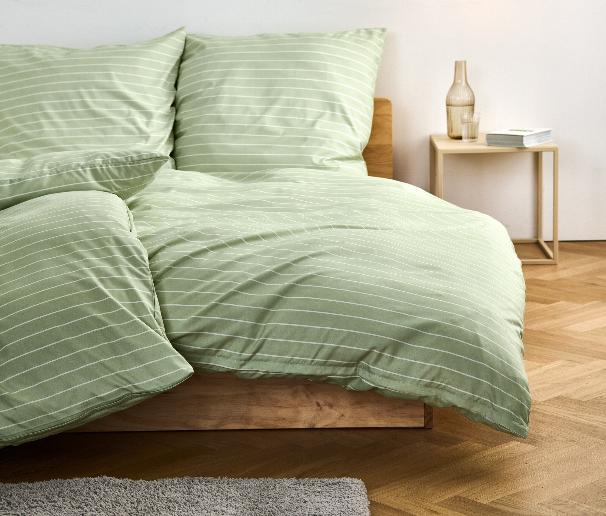 Hellgrüne Microfaser-Bettwäsche, Normalgröße, mit Streifen auf einem Bett.