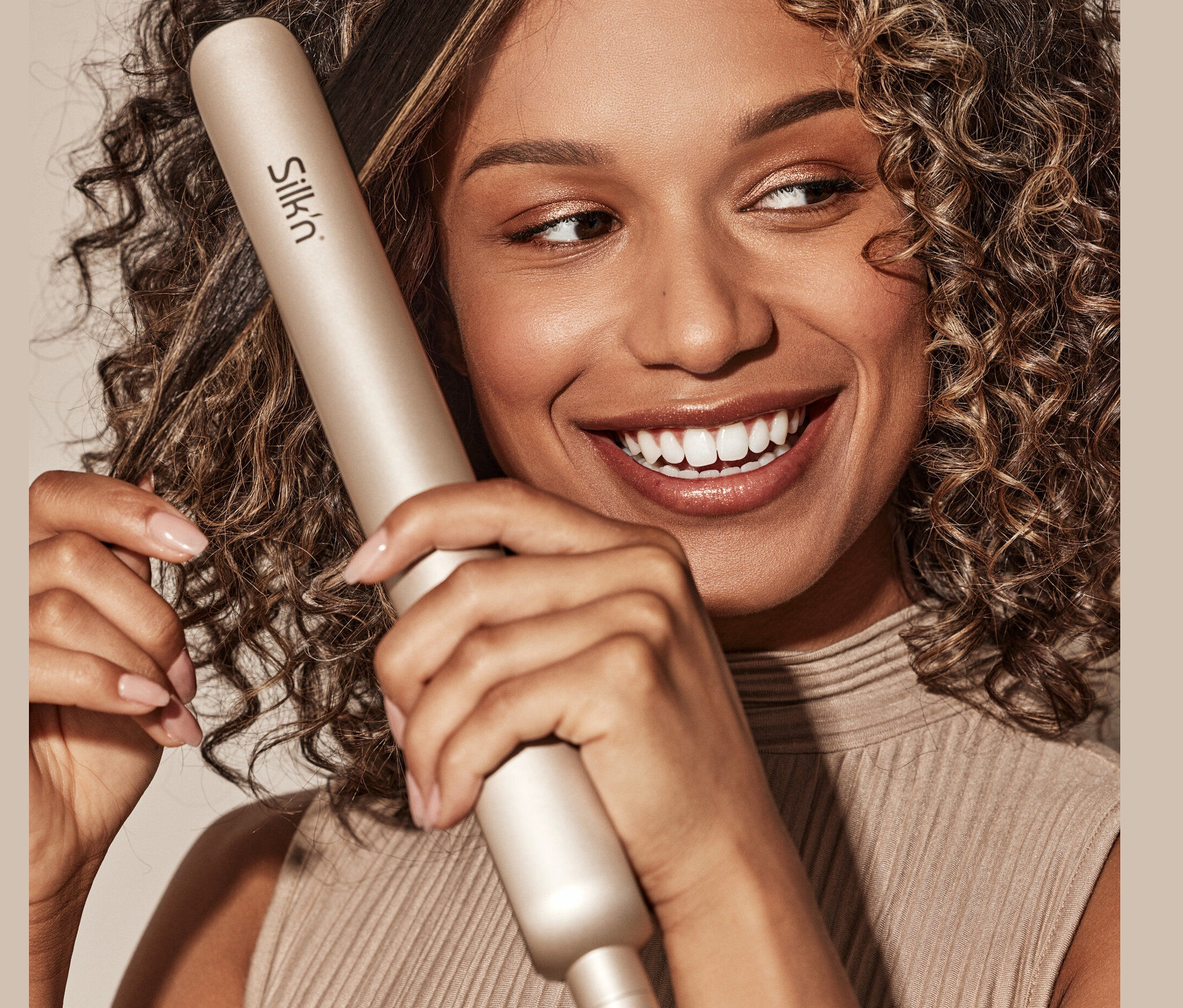 Frau verwendet Silk'n Infrarot Glätteisen »SilkyStraight« auf ihrem lockigen Haar und lächelt.