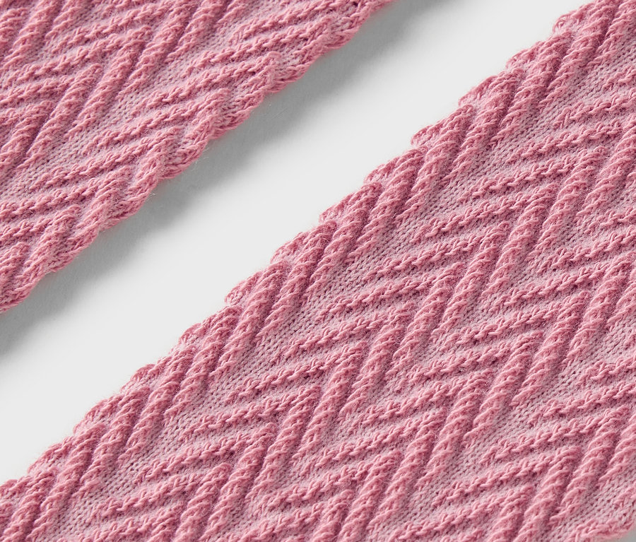 Detailaufnahme von zwei Streifen rosafarbenem Stoff mit Zickzackmuster.