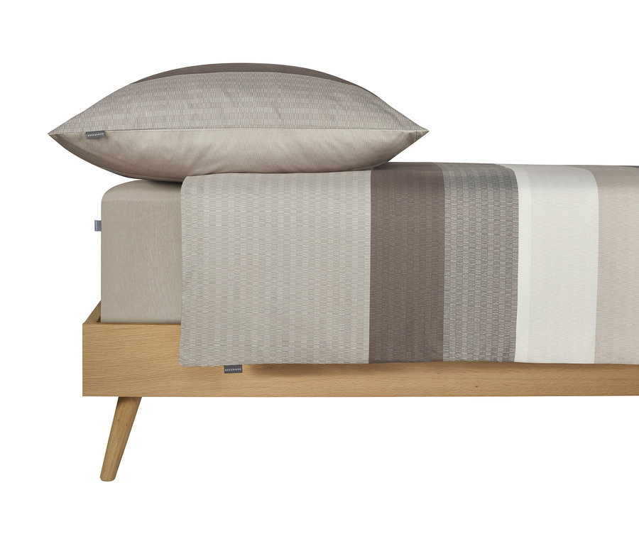 Auf einem Bett liegen ein beiger Kissenbezug und ein gestreiftes Spannbetttuch.