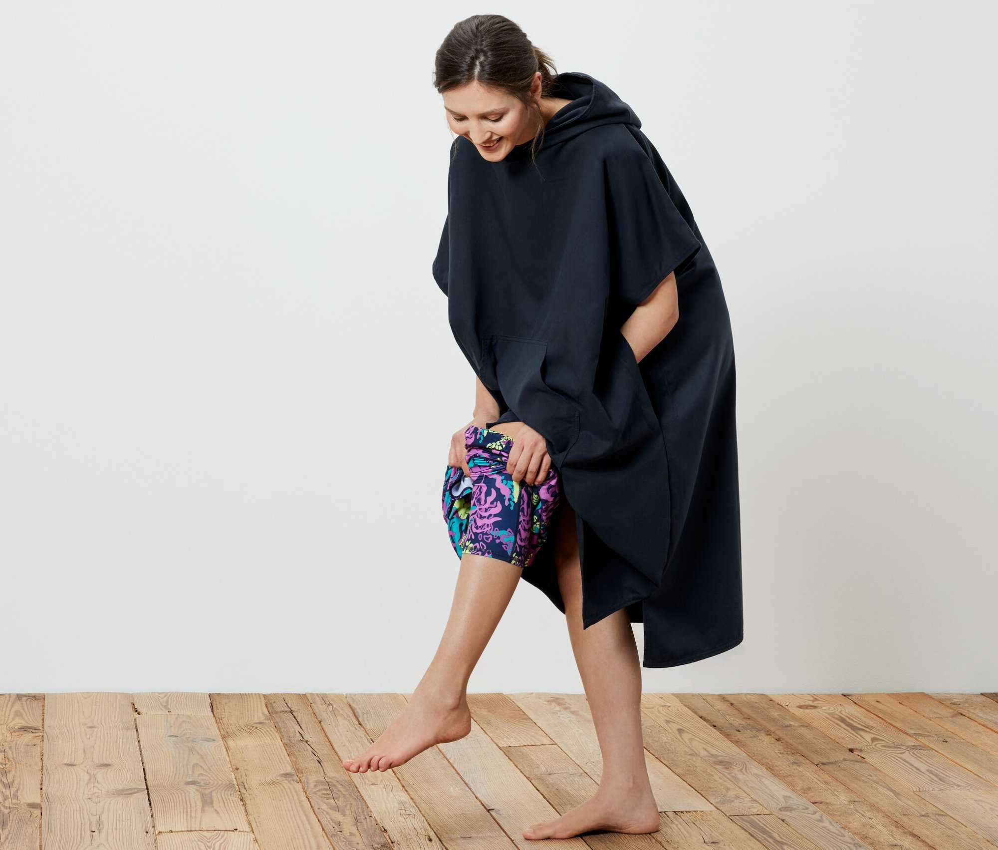 Eine lächelnde Frau zieht einen dunkelblauen Umzieh-Poncho an.