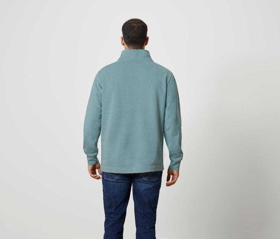 Mann von hinten trägt einen blaugrünen Quarter-Zip-Pullover und Jeans.