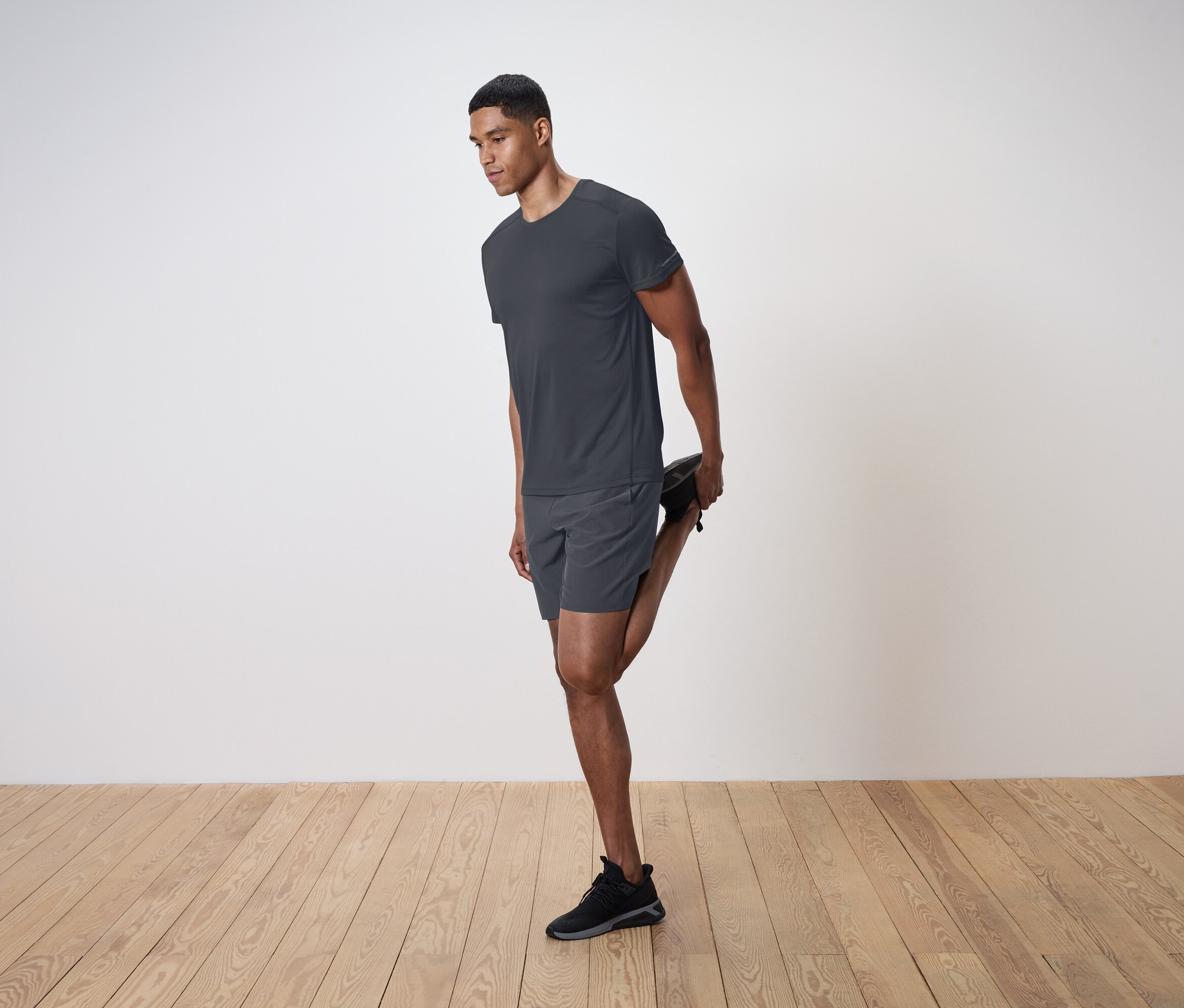 Ein Mann dehnt seinen Quadrizeps vor einer weißen Wand.