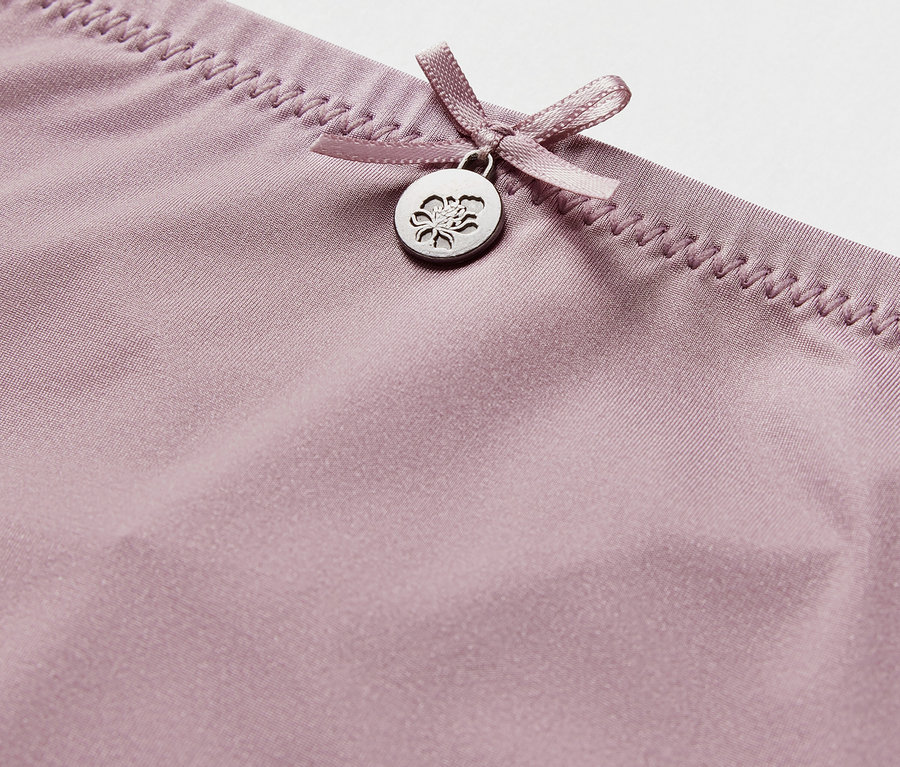 Detailaufnahme eines lila Strings mit Schleife und Anhänger.