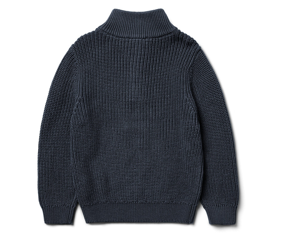 Detailansicht eines dunkelblauen Strickpullovers mit hohem Kragen und Texturmuster.