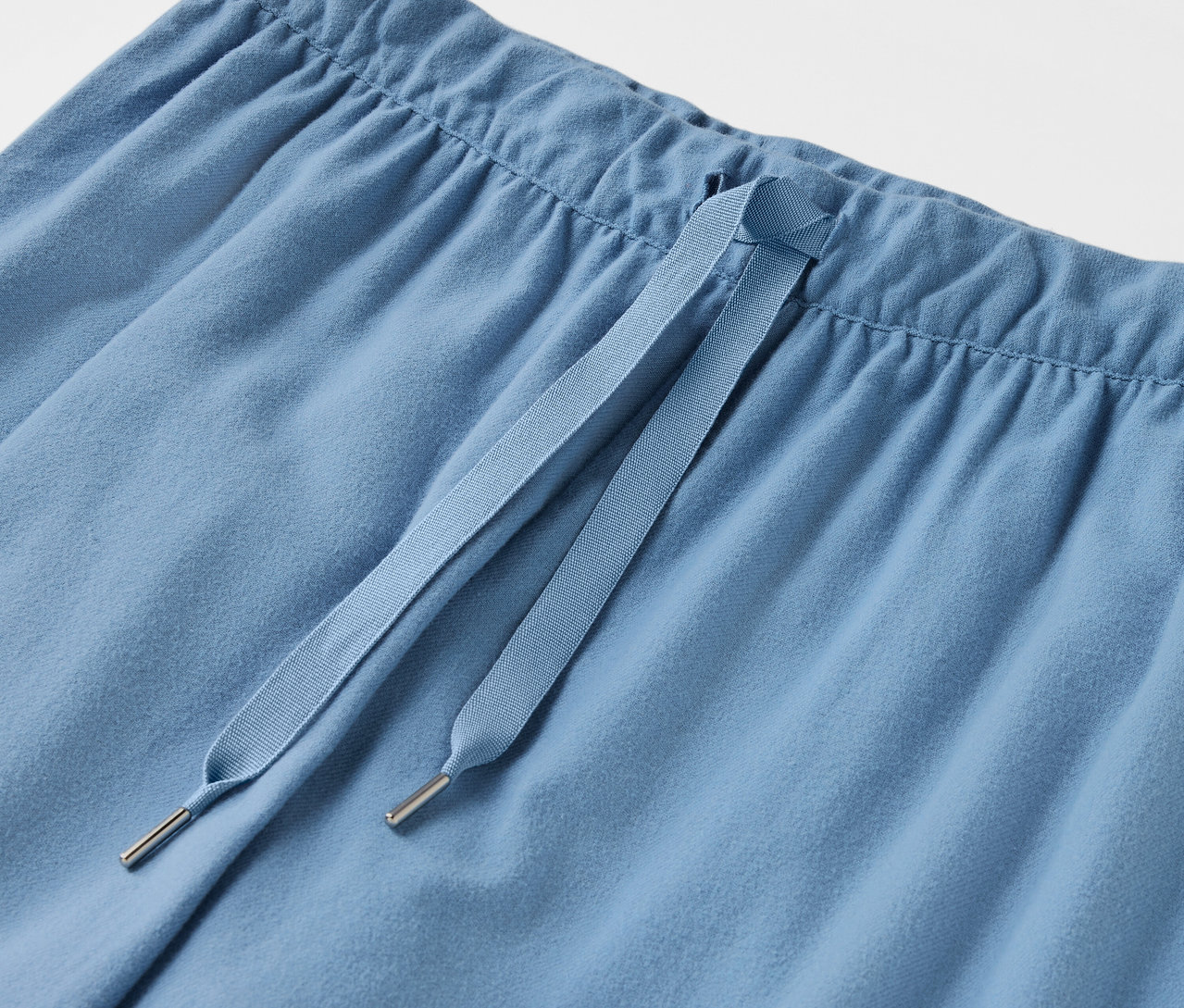 Detailaufnahme einer hellblauen Hose mit Kordelzug.