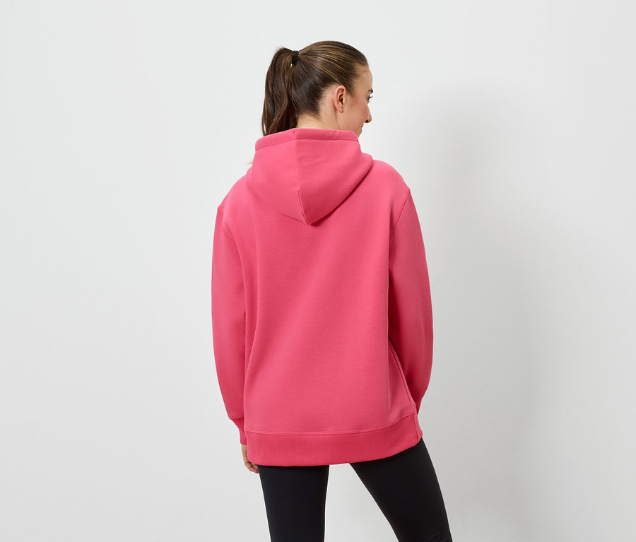 Frau mit dem Rücken zur Kamera trägt einen rosafarbenen Hoodie und schwarze Leggings.