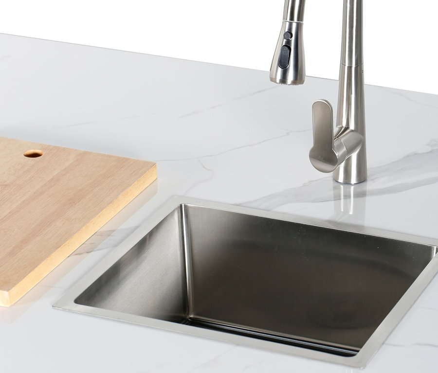 Ein Edelstahlspülbecken und ein Holzbrett auf einer weißen Marmorplatte.