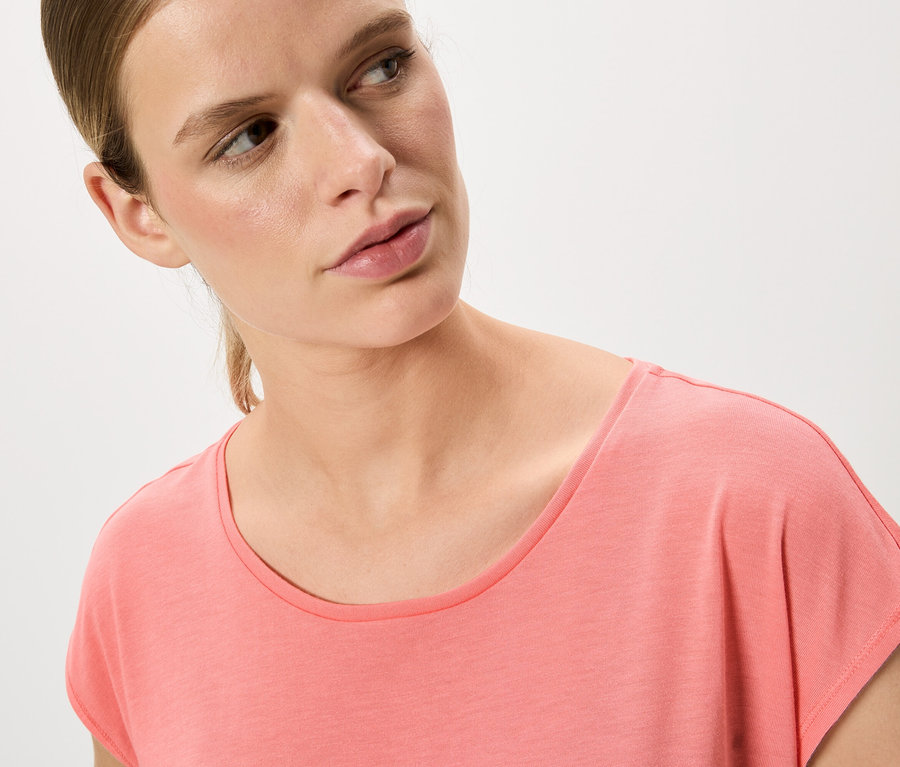 Frau mit blonden Haaren und rosafarbenem T-Shirt.