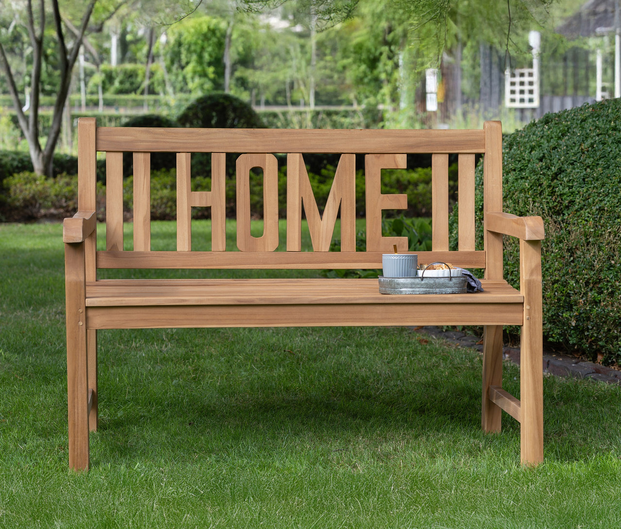 deVries Gartenbank »Home« aus Holz steht auf einer Wiese.