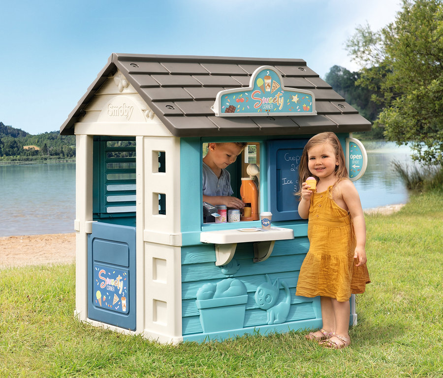 Mädchen isst Eis vor Smoby Life Spielhaus »Sweety Corner«, Junge im Fenster. See im Hintergrund.