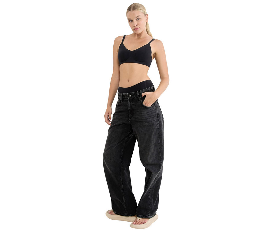 Blonde Frau mit schwarzem BH und locker sitzenden, dunklen Jeans.