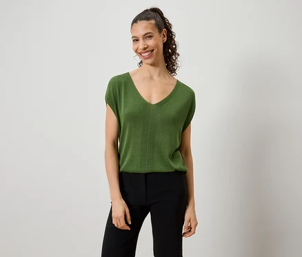 Frau trägt ein grünes Top und eine schwarze Hose.