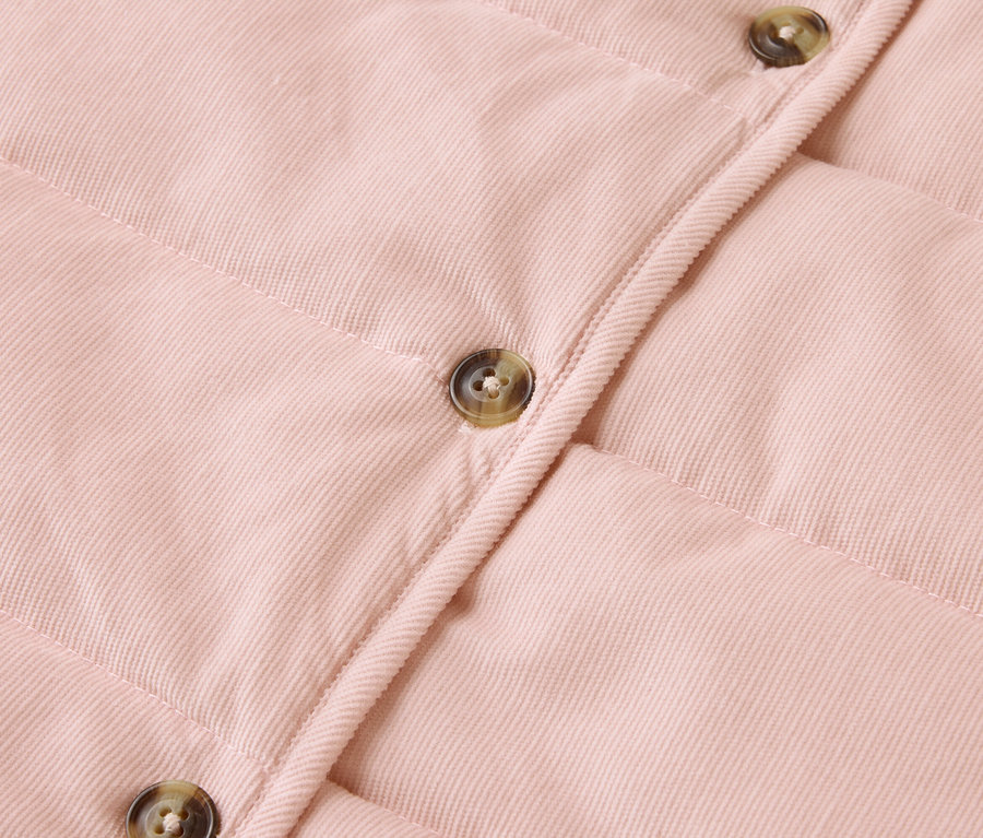 Nahaufnahme einer rosa gesteppten Jacke mit Knöpfen.