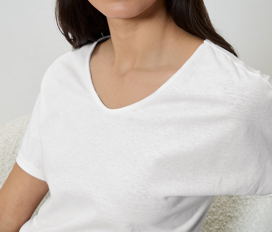 Eine Frau trägt ein weißes T-Shirt mit V-Ausschnitt.